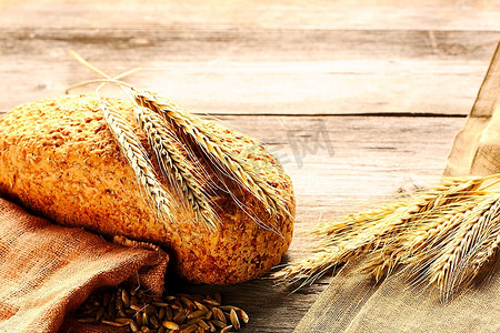 木质背景上的黑麦小穗和面包