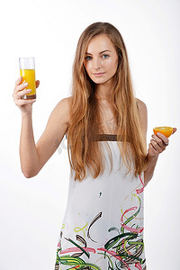 水果半个摄影照片_年轻漂亮的金发女子手里拿着半个橙子和一杯果汁