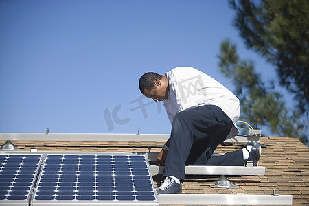 一名男子在屋顶上工作的太阳能板
