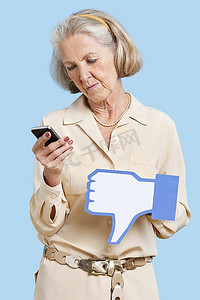 在蓝色背景下，拿着手机的资深女性拿着假的讨厌按钮