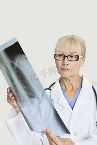 资深女医生在灰色背景上检查X光
