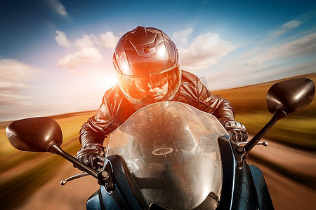 骑摩托车赛车摄影照片_戴着墨镜和皮夹克的摩托车手在路上赛车