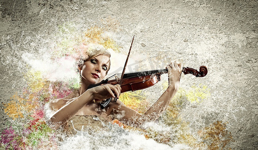 美丽的女小提琴家的形象使用与反对五颜六色的背景的闭上的眼睛