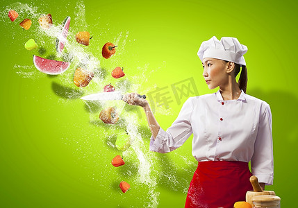 厨师女厨师摄影照片_亚洲女厨师在空中用刀切水果和蔬菜