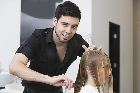 一名男子在理发店为一名年轻女子剪发和梳头