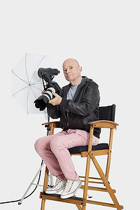 资深摄影师坐在导演和锐利的肖像上；S带相机的椅子