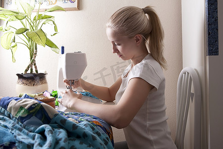 年轻女子坐在缝纫机前缝制拼布