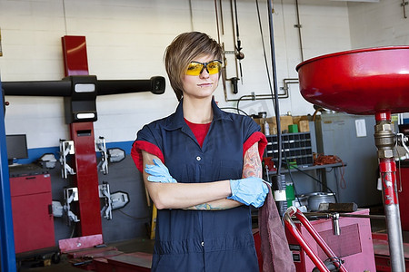 车间里一位穿着防护装备、双臂交叉的年轻女机械师肖像