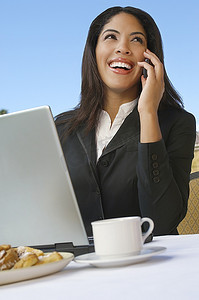中年商务女性在笔记本电脑前打电话