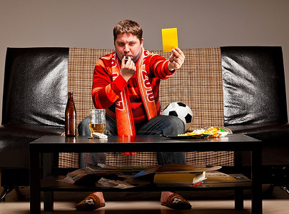 支持者摄影照片_一名足球支持者穿着红色球衣坐在沙发上