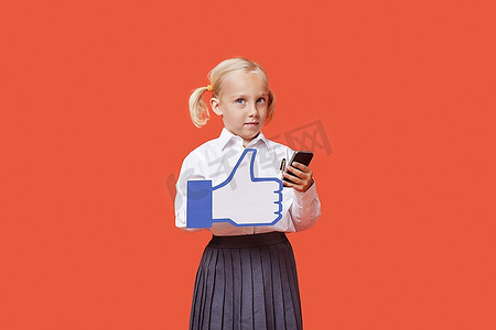 一名年轻女学生的肖像，在橙色背景上拿着手机的假Like按钮