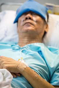 卧病在病床上的成年老年男性患者(手头有选择的焦点)
