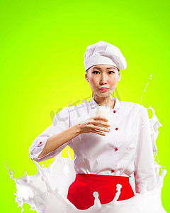 亚洲女厨师手持一杯牛奶，穿着红色围裙，手持牛奶，在彩色背景下飞溅