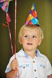 戴着生日帽的小男孩玩气球