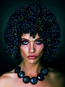 戴头饰的女人摄影照片_秋天女人的肖像，头上戴着葡萄。新潮发型