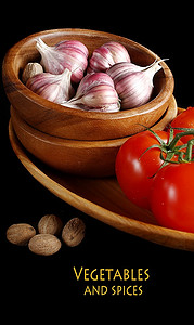 西红柿和大蒜放在木盘里，黑色背景。
