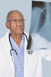 b80摄影照片_非洲裔美国人senor医生分析x射线报告在浅蓝色背景