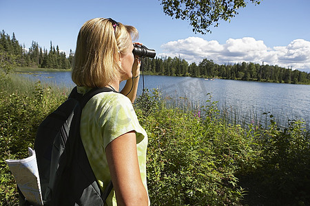 美国，阿拉斯加，妇女通过双筒望远镜在湖