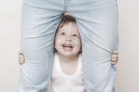 蹒跚学步的孩子抱着妈妈的腿抬起头来