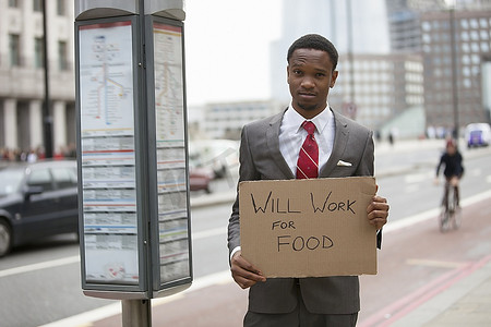 食品标志s摄影照片_年轻的商人举行将工作为食品标志在街上