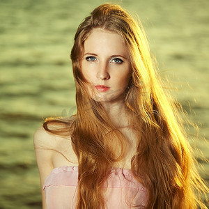 池塘边美丽的红发女孩。美丽的夏日