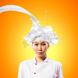 穿着红色围裙的亚洲女厨师站在防止牛奶飞溅的背景下：