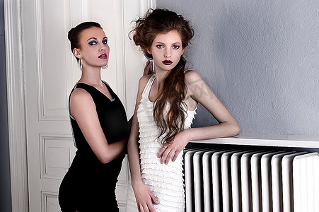 两个发型优雅的美女在室内一扇古老的时尚门前摆姿势