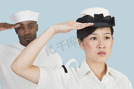 自信的海军女军官和水兵在浅蓝色的背景下敬礼