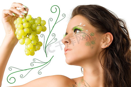 画着脸的漂亮女孩看着手里拿着的绿葡萄