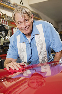 面带微笑的老人在汽车修理店清洗汽车红盖