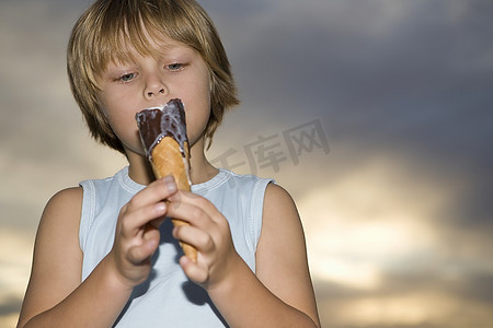 金发女郎7-8岁男孩在背心顶部举行融化巧克力冰淇淋