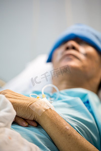 卧病在床摄影照片_卧病在病床上的成年老年男性患者(手头有选择的焦点)