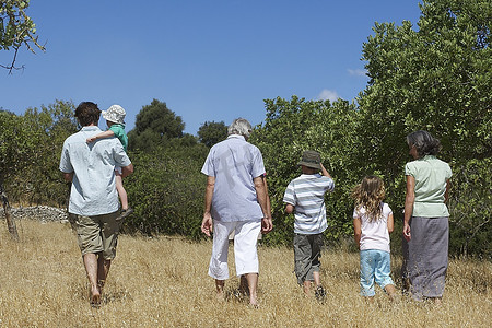 带着三个孩子(3-11岁)的三代家庭在田野里散步，后视镜