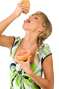张开嘴的漂亮女孩挤着喝着新鲜葡萄柚的果汁