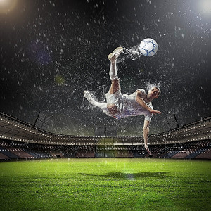 在雨中在体育场击球的白色衬衫的足球运动员