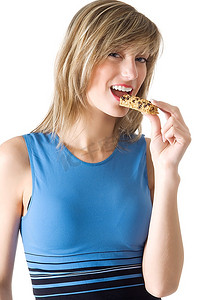穿着蓝色衬衣的金发女孩吃着减肥片，微笑着