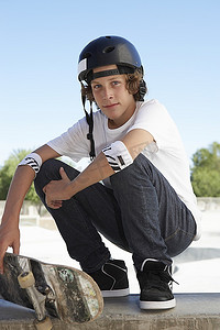 tshirt摄影照片_青少年男孩（16-17）与滑板在滑板公园，肖像