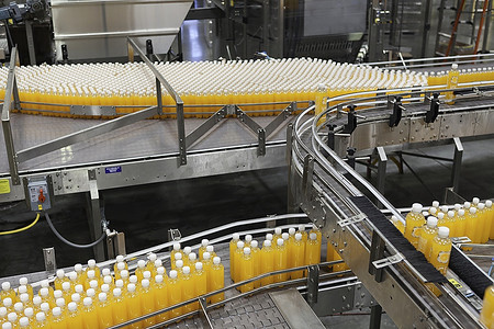 装瓶摄影照片_装瓶厂传送带上的橙汁瓶