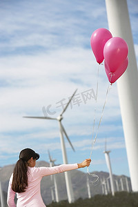 马尾头发摄影照片_女孩（7-9）玩气球在风力农场