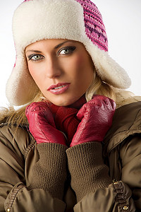 美丽的金发女孩穿着冬装，戴着粉色帽子和红色手套