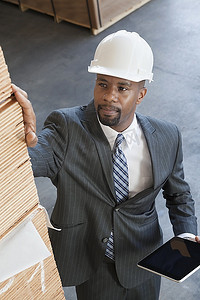 非裔美国男性承包商手持平板电脑检查木板的高角图