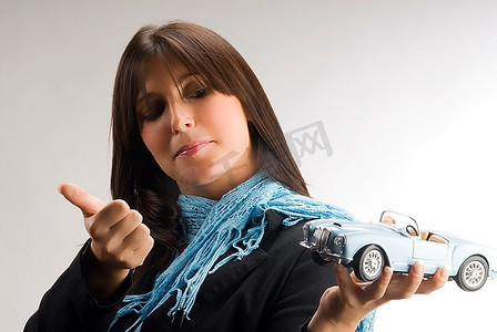 特例摄影照片_一位年轻优雅的女士饶有兴趣地看着一辆蓝旗亚汽车模型