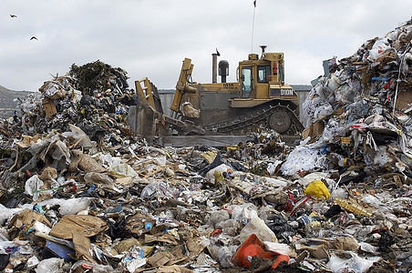 禁止垃圾桶矢量图摄影照片_挖掘机在垃圾填埋场移动垃圾