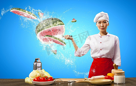 刀切水果摄影照片_亚洲女厨师在空中用刀切水果和蔬菜