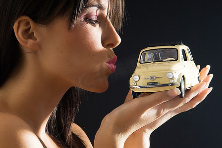 特例摄影照片_漂亮年轻的黑发女郎与一辆意大利风格的菲亚特500汽车接吻