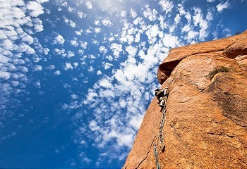 攀岩：攀登者在蓝天之上陡峭的花岗岩悬崖上攀登。阿特拉斯山脉，南马鲁克，非洲。