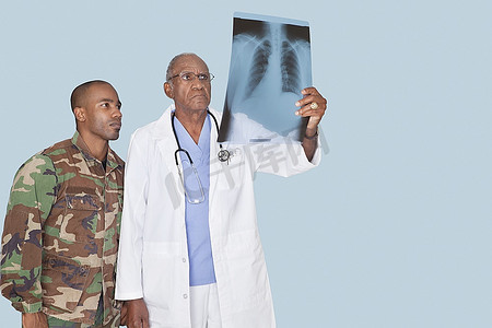 美国海军陆战队士兵在浅蓝色背景下查看X光报告的高级医生