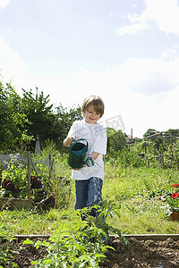 植物b摄影照片_男孩在花园里给植物浇水