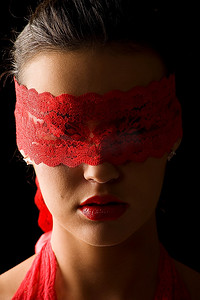 神秘面具人摄影照片_一幅漂亮而神秘的年轻黑发肖像，背景是黑色，戴着红色蕾丝面具