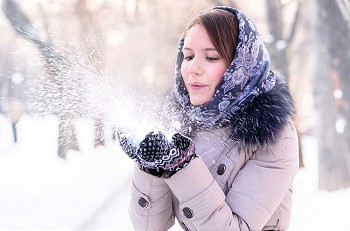 一位年轻女子在冬日公园里吹雪